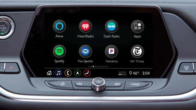 Car infotainment system display featuring apps like Spotify, Pandora, iHeartRadio, and Fox Sports, along with controls for voice assistance and connectivity options. The screen shows the temperature at 46°F and the time as 3:04.