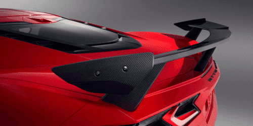 Close-up view of a sleek red sports car showcasing its rear engine cover, featuring a distinctive design and vent details that enhance aerodynamics and performance.
