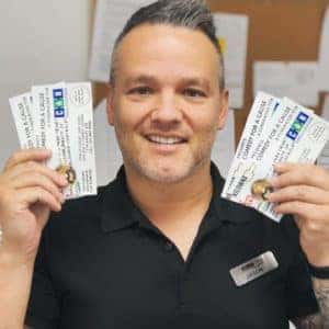 Man smiling and holding several identification cards, showcasing a welcoming atmosphere in a personal service environment.