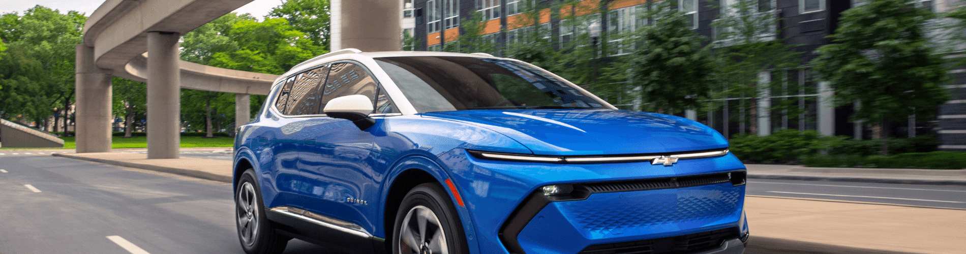 Sleek blue Chevrolet SUV parked in front of a modern glass building, showcasing bold design features, sporty wheels, and a striking front grille suitable for urban driving and outdoor adventures.