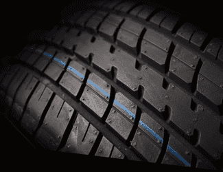 Close-up of a high-performance tire showcasing deep tread patterns and a blue center stripe, emphasizing grip and traction for enhanced road performance.