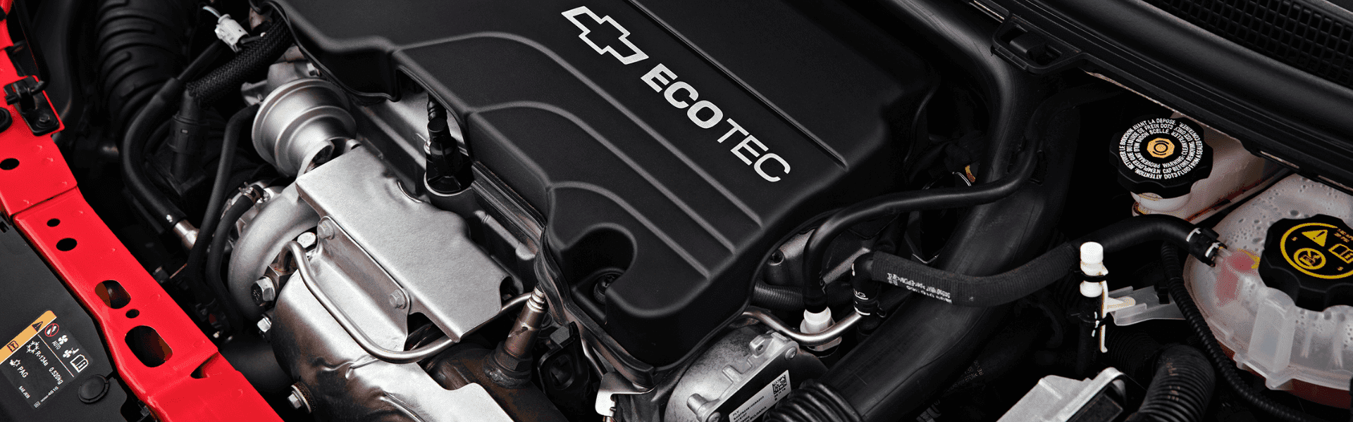 Close-up view of a Chevrolet Ecotec engine showcasing key components, including the aluminum intake manifold, turbocharger, and various hoses, highlighting its modern automotive engineering and design.