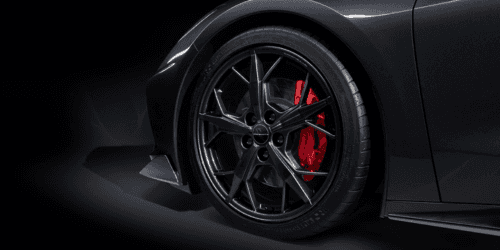 Close-up view of a sleek red sports car showcasing its rear engine cover, featuring a distinctive design and vent details that enhance aerodynamics and performance.