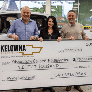 Kelowna Chevrolet representatives presenting a large check for $50,000 to the Okanagan College Foundation, dated December 13, 2019, during a holiday event.