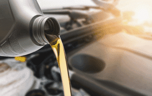 Engine oil being poured from a bottle into a vehicle engine, showcasing the importance of regular oil changes for vehicle maintenance.