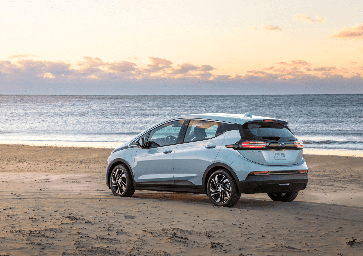 Modern Chevy electric SUV parked in front of a contemporary building, showcasing sleek lines and innovative design. The vehicle stands out with its aerodynamic shape and stylish wheels, emphasizing its advanced technology and eco-friendly features.