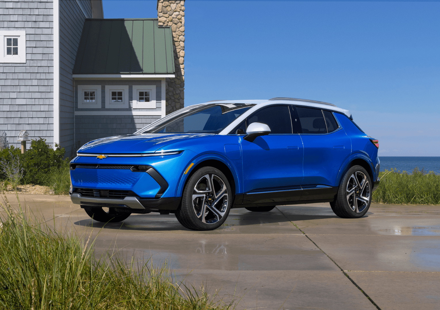 Modern Chevy electric SUV parked in front of a contemporary building, showcasing sleek lines and innovative design. The vehicle stands out with its aerodynamic shape and stylish wheels, emphasizing its advanced technology and eco-friendly features.