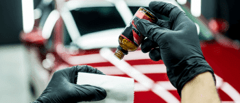Close-up of a technician applying protective film to a vehicle's hood, demonstrating a paint protection film installation process to shield the car’s surface from scratches and damage.