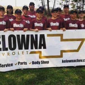 Group photo of a youth sports team posing with a sponsorship banner for Kelowna Chevrolet, showcasing team uniforms and the brand's logo.