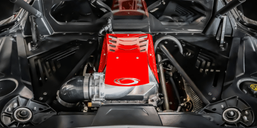 High-performance car engine with a striking red intake manifold, showcasing advanced engineering and design, viewed from above against a sleek black backdrop.