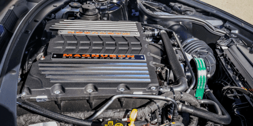 Close-up view of a Magnuson supercharger installed in a car engine compartment, showcasing its sleek design and advanced engineering for improved performance.