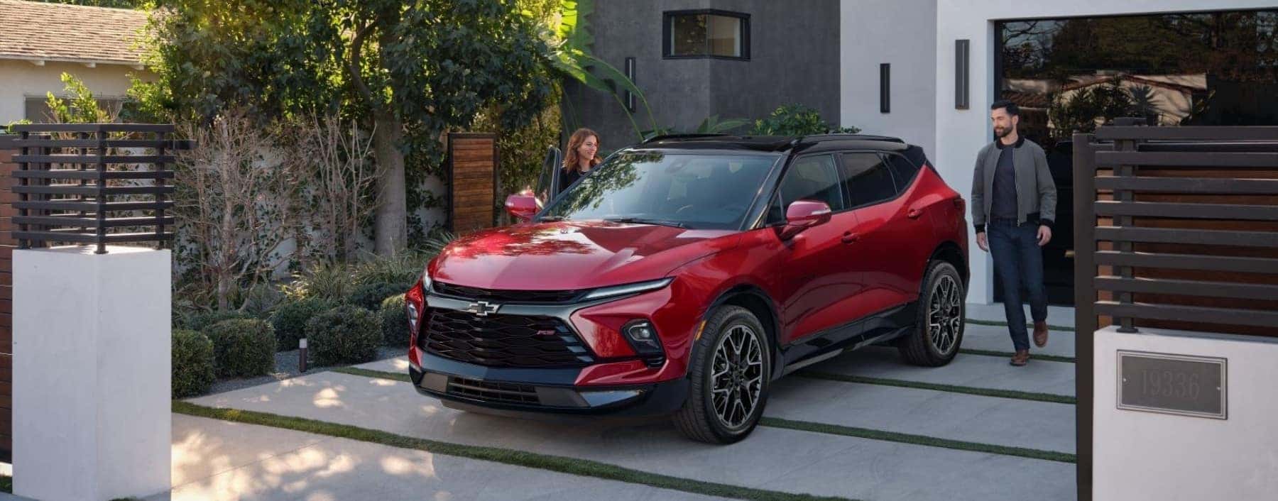 Sleek red Chevrolet SUV parked in front of a modern glass building, showcasing bold design features, sporty wheels, and a striking front grille suitable for urban driving and outdoor adventures.